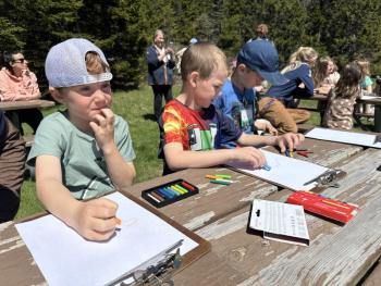 children work with crayons at a picnic table