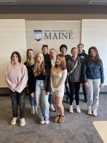 teen group photo in front of a UMaine logo