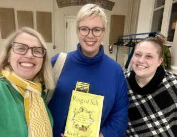 Three women pose with book