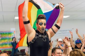 Person raising rainbow flag above the head