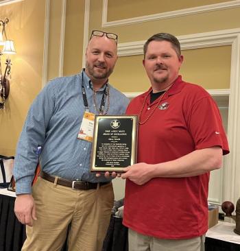 Two men pose with plaque