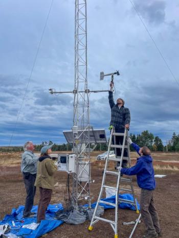 Four people work around tower