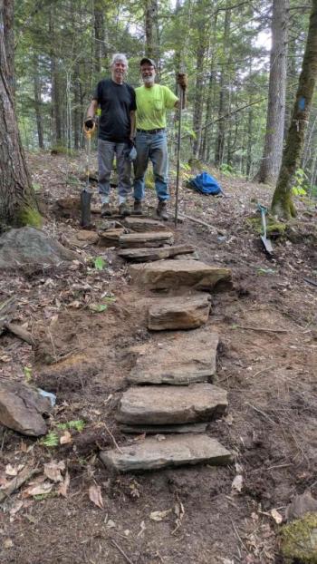 Two men stand at top of rock steps