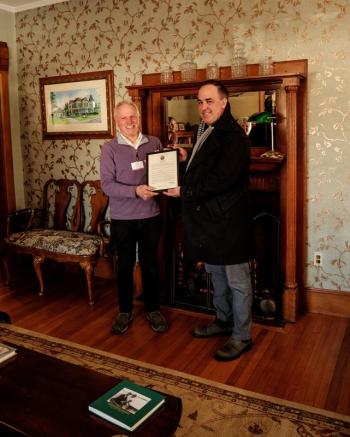 Two men hold framed proclamation