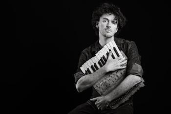 person holding instrument in front of black background