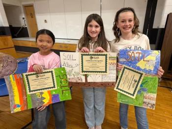 three kids stand with posters