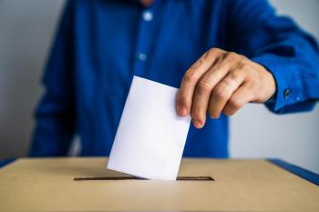 a man inserts his ballot into a box