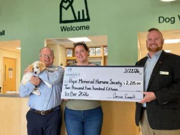 Three adults and a dog pose with oversize check