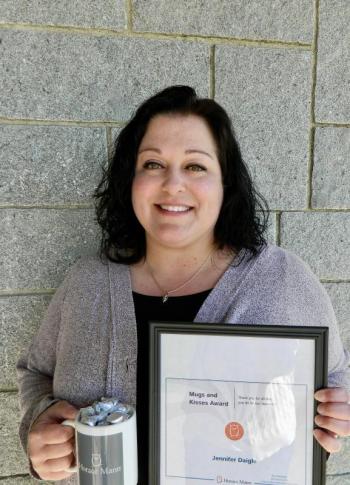 woman holds framed certificate, mug of chocolates