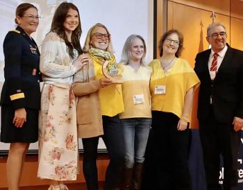six adults pose with award