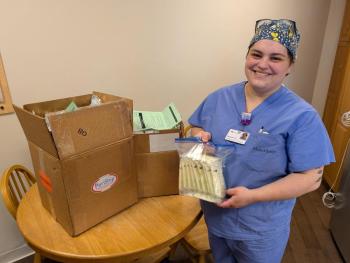 woman in scrubs poses with donation kit