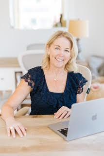 smiling woman looks up from laptop