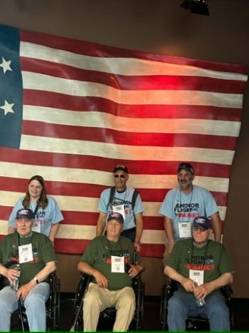 three sets of participants in front of flag
