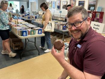 man holding doughnut at book sale