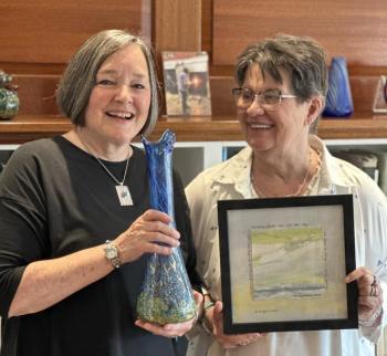 two women pose with examples of their art