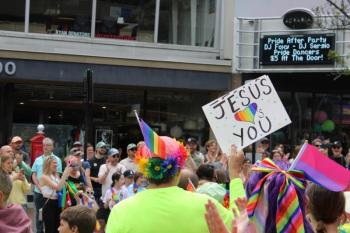 A man holds a sign that reads Jesus loves you