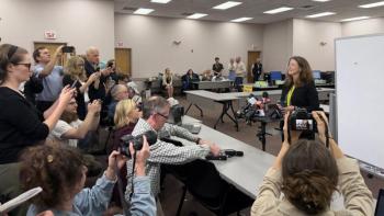 journalists crowd around an election official 