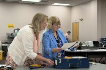 election officials look at pieces of paper.