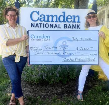 two women pose with presentation check