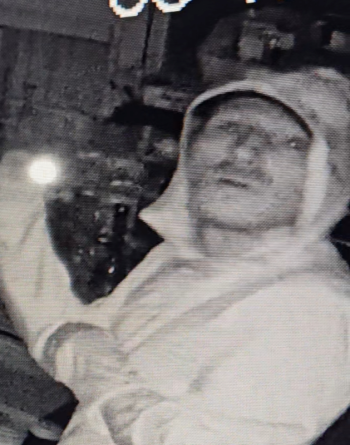 A still from a security video shows the suspect looking around the store with a flashlight. This photo was released to the public in an effort to identify the man. 