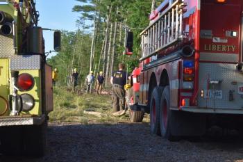People with hard hats walk toward fire trucks