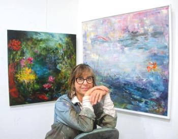 woman poses in front of paintings