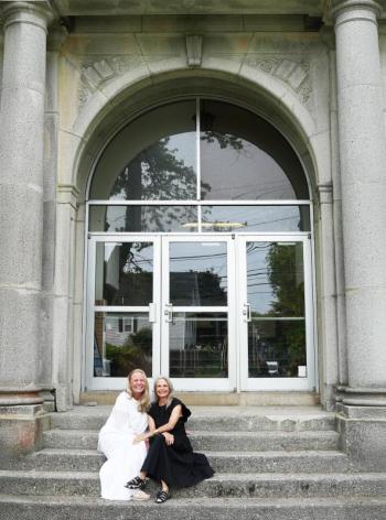 women sit on front steps to building
