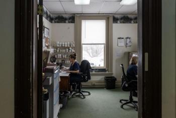 two women reviewing paperwork while sitting at desks