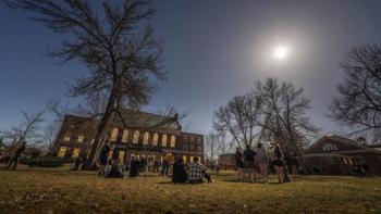 people on lawn looking toward the sun