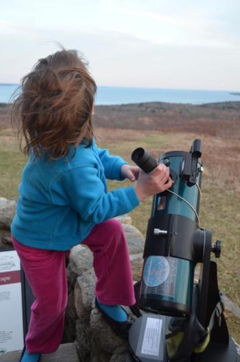 young child gripping telescope