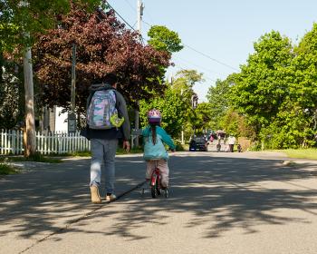 children wearing backpacks ride bikes