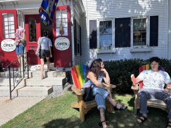 shopper enters store while two others sit in Adirondack chairs
