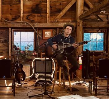 male playing guitar in barn