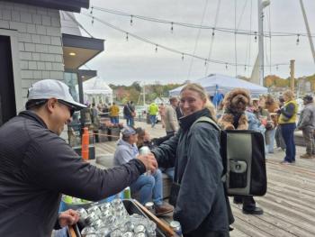 Mast Landing's Gabe Vickery hands Kathryn Rogers from Owls Head a beer as she, and her backpack buddy, Ziggy, enjoy the festival. Photo by Kay Stephens