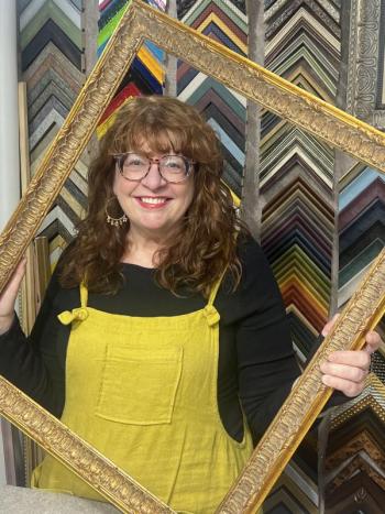 woman poses through empty picture frame