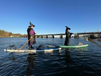 witches stand on paddle boards