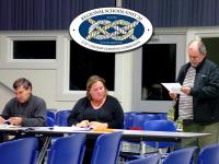 Belfast City Councilor Mike Hurley, right, searches for safe topics on the agenda at the Nov. 12 meeting of the RSU 20 board of directors. Seated are Belfast board members Caitlin Hills and Alan Wood. (Photo by Ethan Andrews)