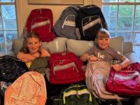 Two future Rotarians are all smiles as they help unload this year’s donation of 90 backpacks from L.L. Bean.