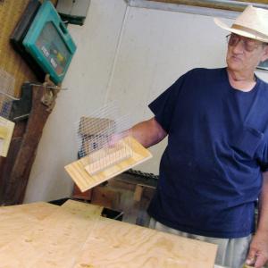 In his workshop, Adrian Turner shows the wire mesh interior of one of his bat houses.