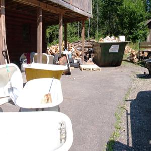 Mr. Tubs, surrounded by unrestored bathtubs takes a call outside his workshop. (Photo by Ethan Andrews)
