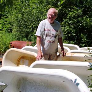 Bill Coughlin, a.k.a. "Mr. Tubs," with some of the dozens of cast iron tubs he keeps outside his Belmont workshop. (Photo by Ethan Andrews)
