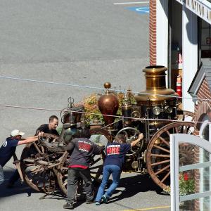 Andy Swift of Firefly Restoration in Hope, second from left, helps push Camden Fire Department's 1892 Amoskeag horse-drawn steam fire pumper into a bay at the station Tuesday, Sept. 11.