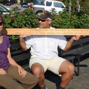 Camden Harbormaster Steve Pixley holds a newly engraved memorial bench plank alongside Marta Koonz.
