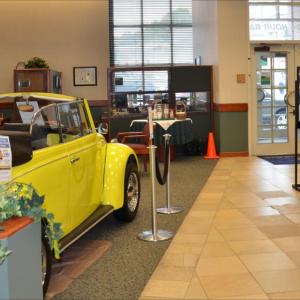 The 1968 Volkswagen Beetle sits in the lobby of Camden National Bank, in downtown Camden. Its owner, Josey Lewis, an employee of the Camden downtown branch of the bank, stands beside it. She always wanted a beetle, and four years ago, bought herself one. The license plate reads "Sew Nutt", reflecting her hobby as a seamstress. (Photo by Lynda Clancy)