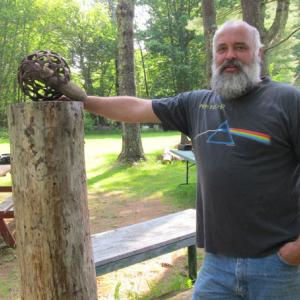 Artist Jay Sawyer posing with one of his welded spheres, Rock N Roll