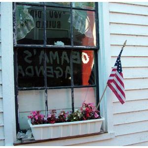 Slogans from Americans for Prosperity's "Obama's Failing Agenda" tour bus reflect in the window of the Dirigo Grange Hall in Freedom Sept. 17. The bus, which has been traveling the East Coast since Labor Day, made the Western Waldo County town one of three stops in Maine. (Photo by Ethan Andrews)