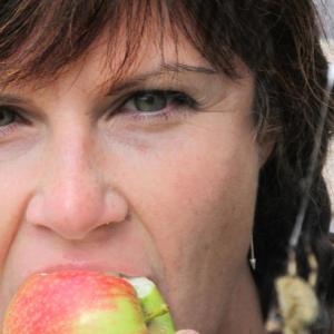Nadine Gallagher as Snow White taking a bite of the poisoned apple next to an enormous barn spider.