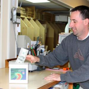Heath Commeau, manager of Global Packing and Shipping Camden, makes a donation for Hurricane Sandy relief Monday. (Photo by Holly S. Edwards)