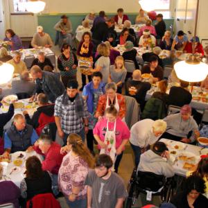 As the dining hall fills with people, volunteers hurry about to start serving meals. (Photo by Chris Wolf)