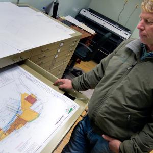 Front Street Shipyard President JB Turner with drawings of the Shipyard property and proposed additions. Turner and fellow representatives of the business anticipate making a formal presentation of their ideas, some of which would require the use of city property at the Dec. 4 City Council meeting. (Photo by Ethan Andrews)